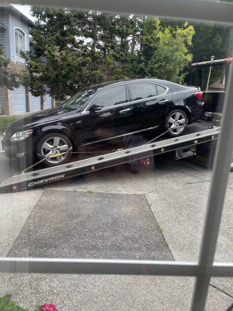 A black sedan being loaded onto a flatbed tow truck by Speed's Towing in Vancouver, WA.