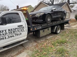 A black sedan loaded onto a flatbed tow truck, providing towing services by Swift Response Road Services, LLC in Memphis, TN.