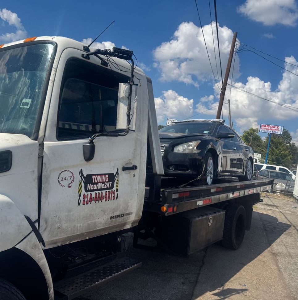 A black sedan loaded onto a flatbed tow truck from Towing Near Me 247 LLC Dallas in Dallas, TX.