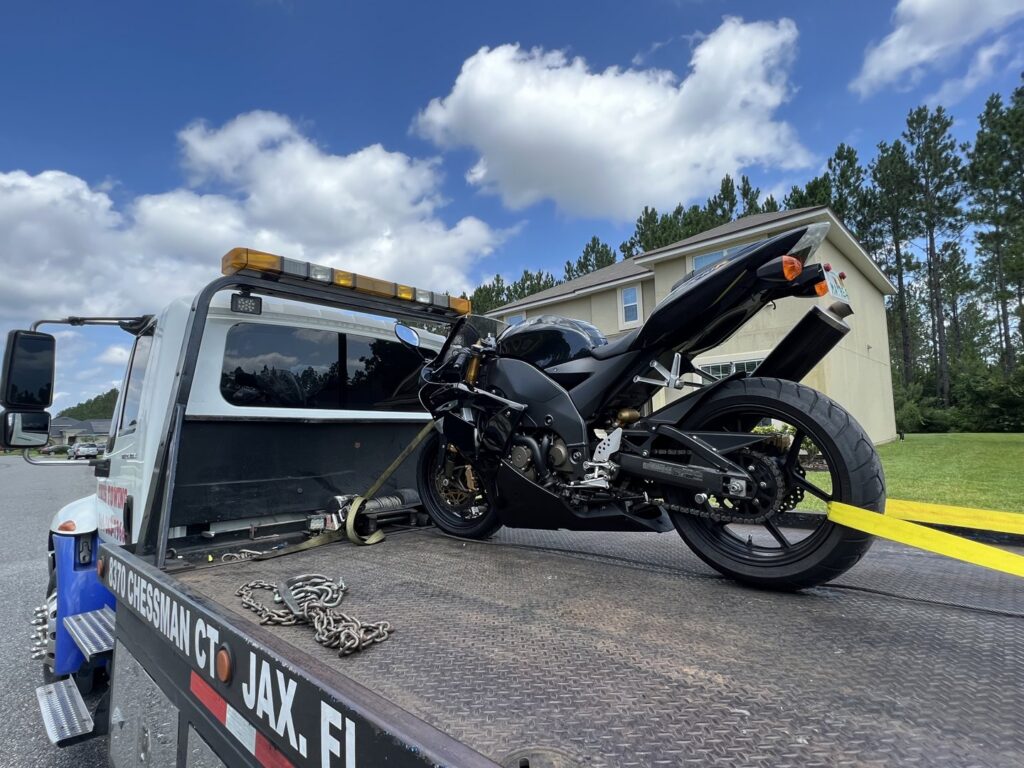 A black sportbike motorcycle being transported on a flatbed tow truck by Tiki's Towing LLC in Jacksonville, FL.