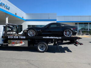 A black sports car being transported on a flatbed tow truck by All Roadside Towing San Diego, CA.