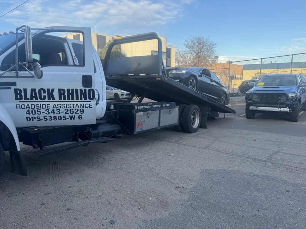 A black sports car being towed on a Black Rhino Towing flatbed truck by Black Rhino Towing in Denver, CO.