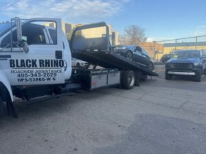 A black sports car being towed on a Black Rhino Towing flatbed truck by Black Rhino Towing in Denver, CO.