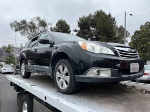A black Subaru Outback being transported on a flatbed tow truck by All Roadside Towing San Diego, CA.
