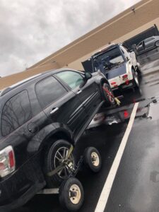 A black SUV being towed with a dolly system by a J & G Towing, LLC truck in Greensboro, NC.