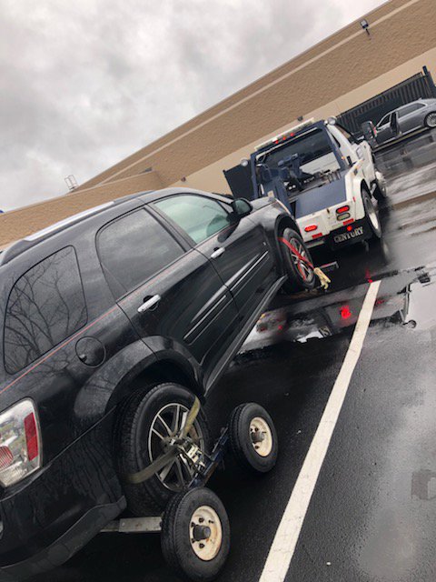 A black SUV being towed with a dolly system by a J & G Towing, LLC truck in Greensboro, NC.