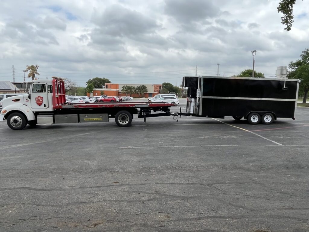A black SUV being loaded onto a flatbed tow truck by AB Towing & Transport in San Antonio, TX.