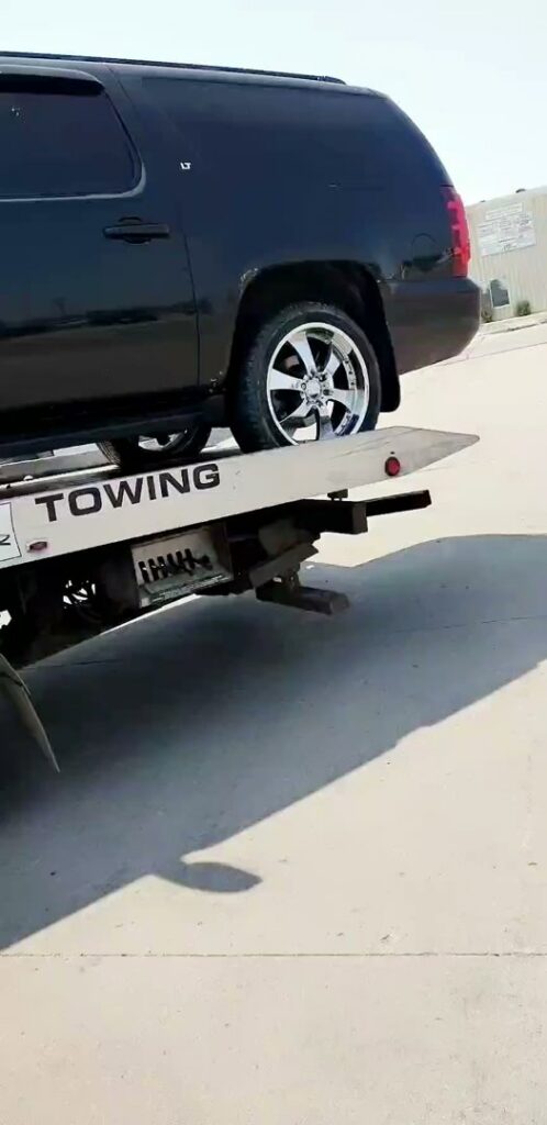 A black SUV loaded onto a flatbed tow truck by Geely Towing in Fargo, ND.