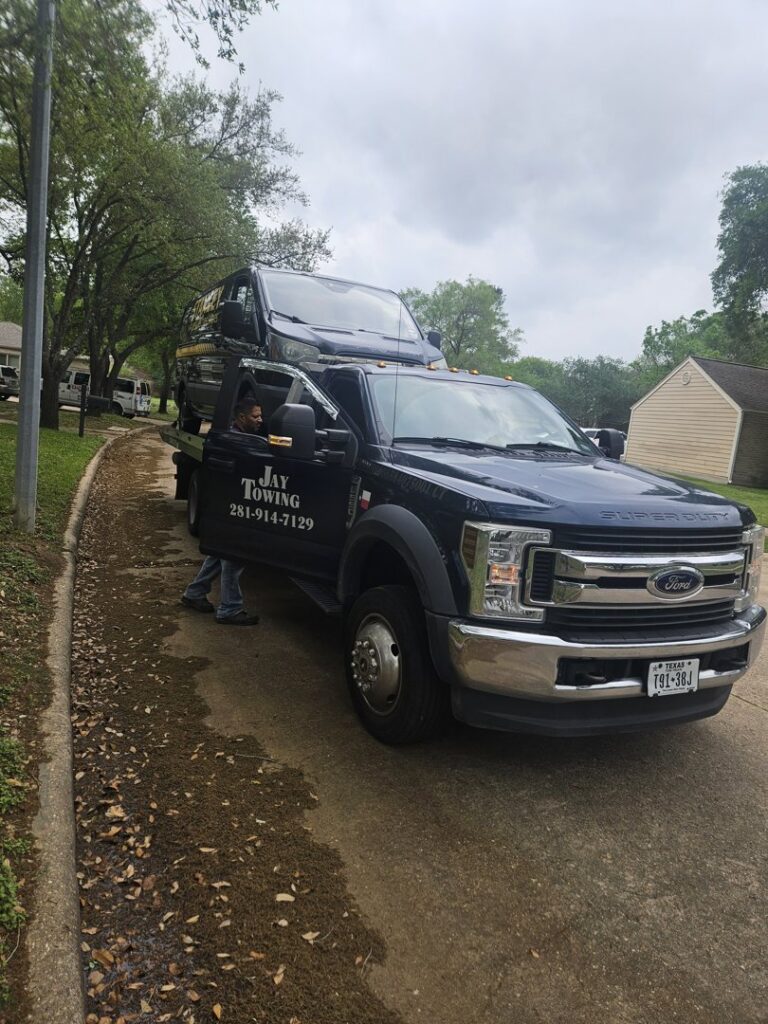 A black SUV loaded onto a flatbed tow truck from Jay Towing Services, ready for transport in Houston, TX.