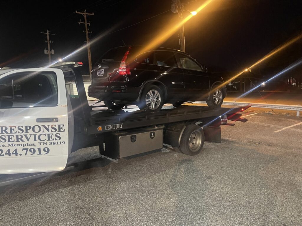 A black SUV loaded onto a flatbed tow truck at night, providing towing services by Swift Response Road Services, LLC in Memphis, TN.