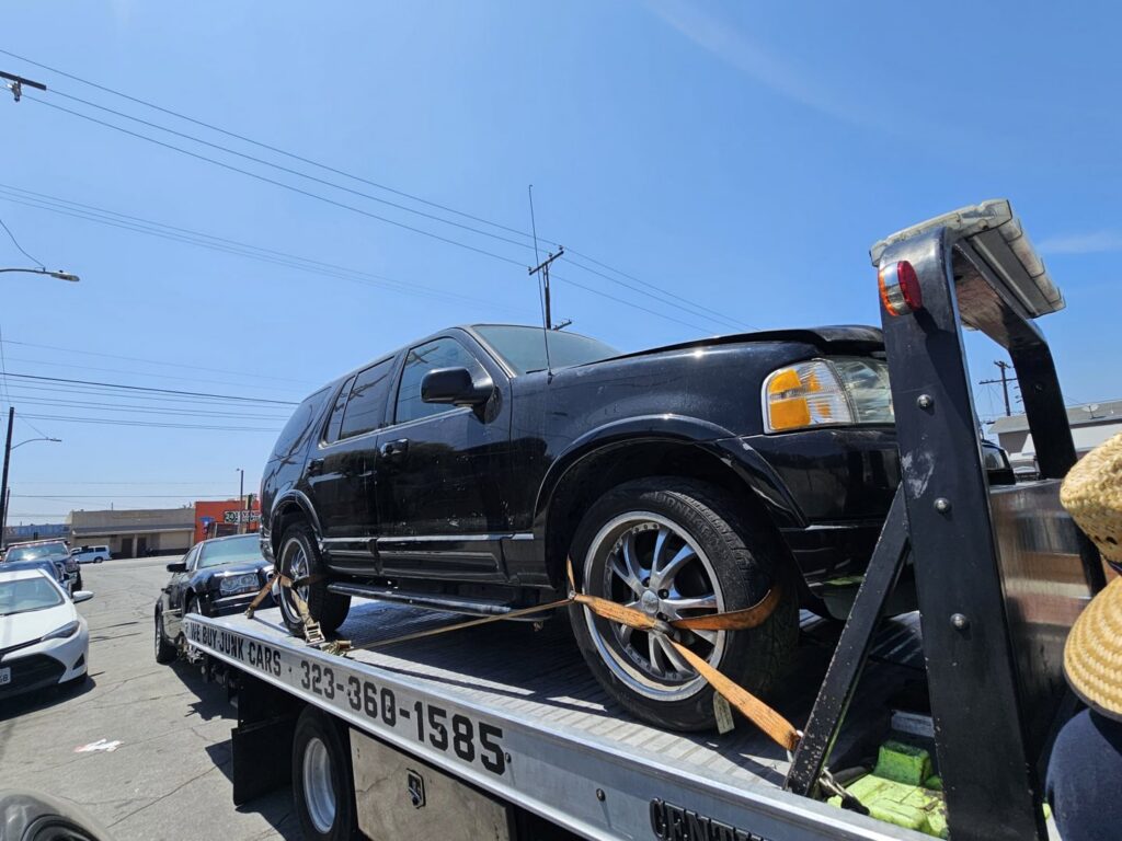 A black Ford Explorer SUV loaded onto a flatbed tow truck by Orellanas Towing & Junk Car in Los Angeles, CA.