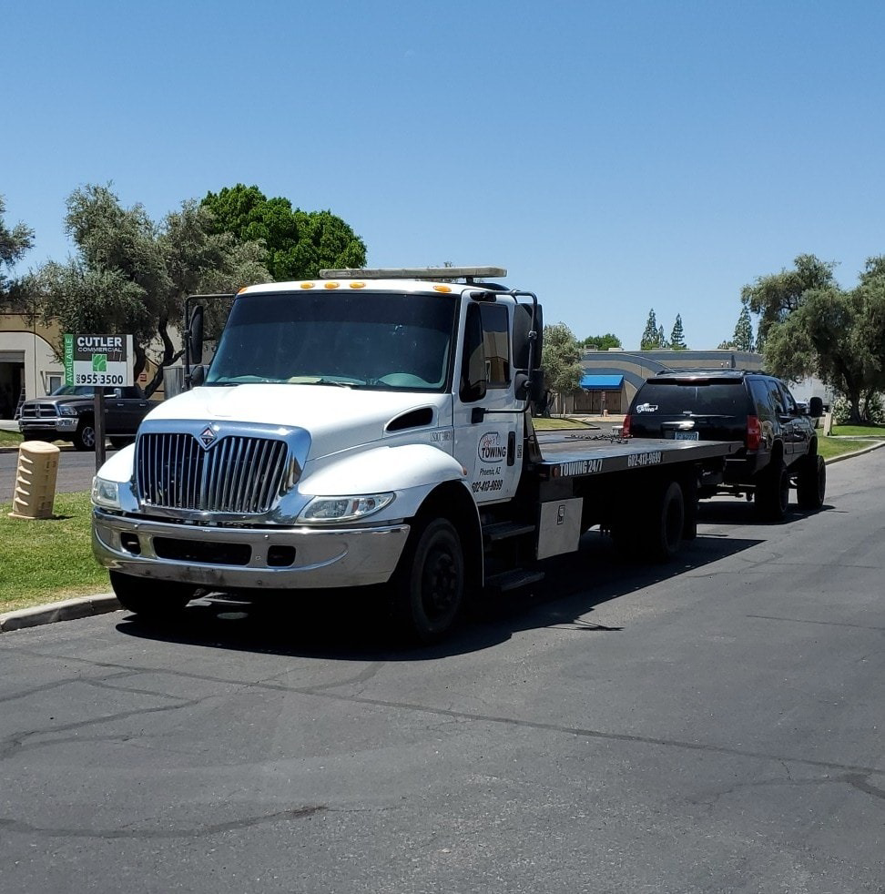 A black SUV loaded onto a flatbed tow truck operated by Rojo's Towing in Phoenix, AZ.