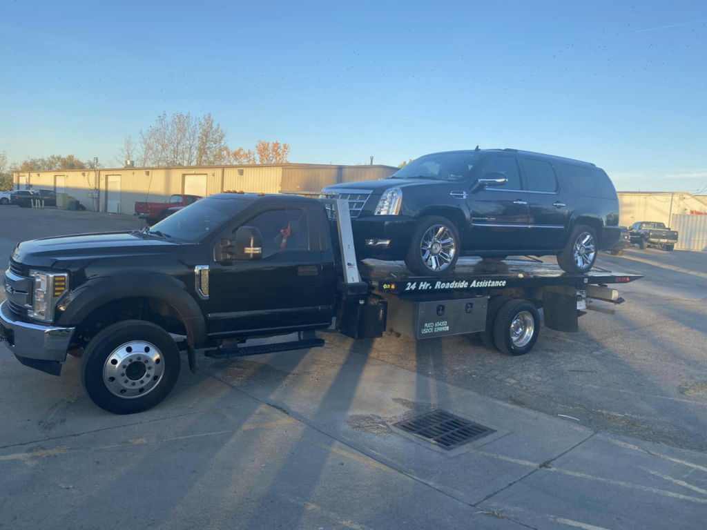 A black SUV being transported on a flatbed tow truck by Triple T's Tow, Tire, & Transportation in Cincinnati, OH.