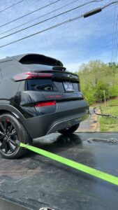 A black SUV being secured with green straps onto a flatbed tow truck by Tow Truck Company in Johnson City, TN.