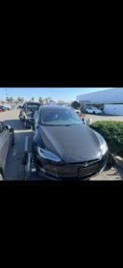 A black Tesla car on dollies, ready for towing by R towing Services in Sacramento, CA.