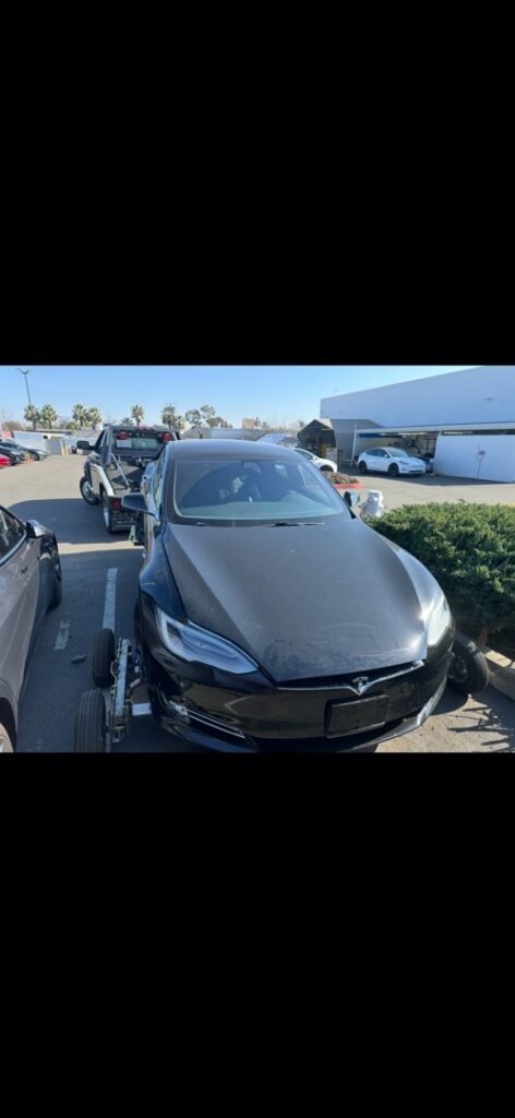 A black Tesla car on dollies, ready for towing by R towing Services in Sacramento, CA.