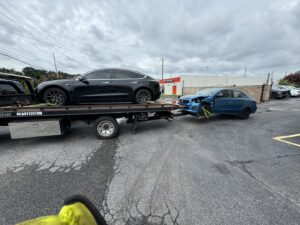 A black Tesla securely loaded onto a flatbed tow truck by Hampton Roads Towing Services in Chesapeake, VA.
