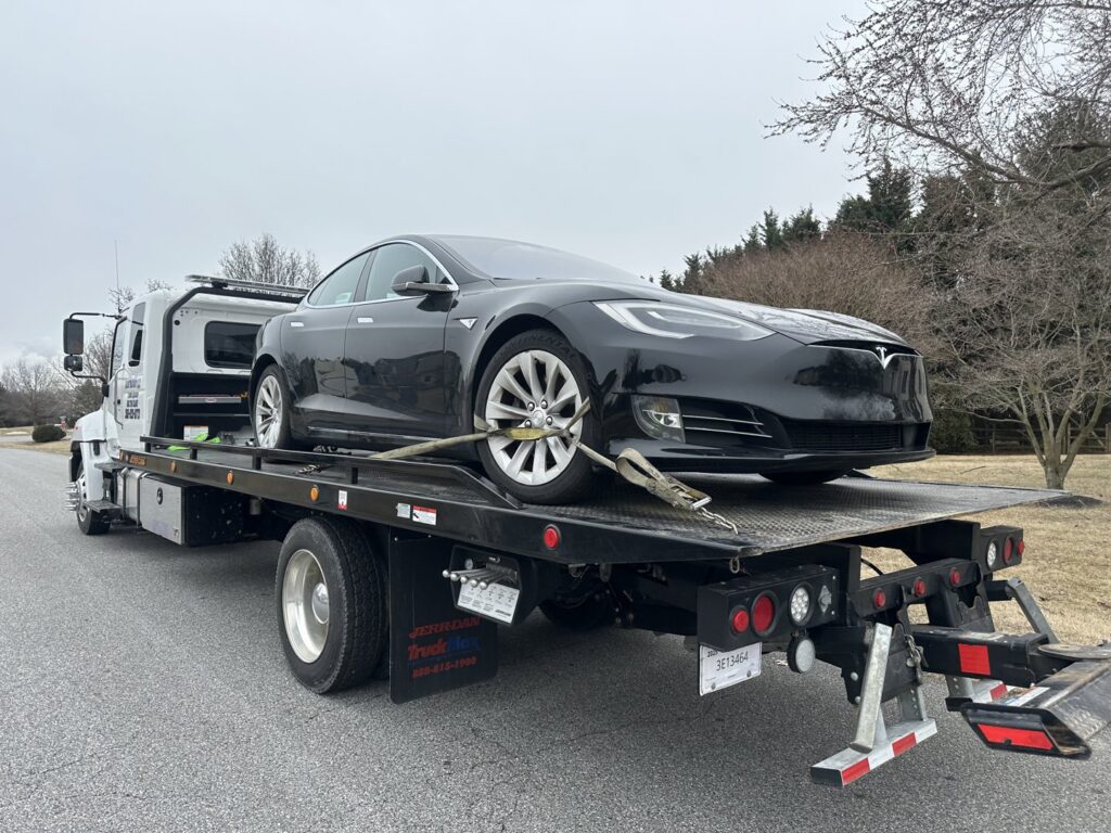 A black Tesla loaded onto a flatbed tow truck from Nacho Transports llc in Middletown, DE.