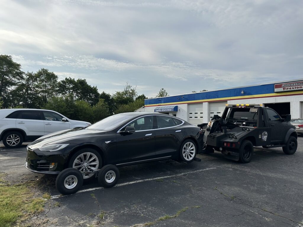 A black Tesla being towed with dollies by Nacho Transports llc in Middletown, DE.