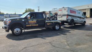 A black tow truck from Terry's Auto Service and Towing, LLC, towing a Garda armored van in Springfield, MO.