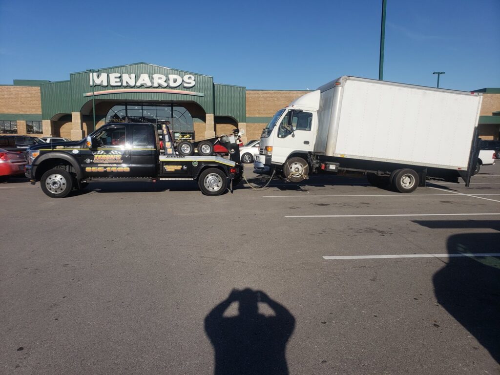 A black tow truck from Terry's Auto Service and Towing, LLC, towing a white box truck in Springfield, MO.