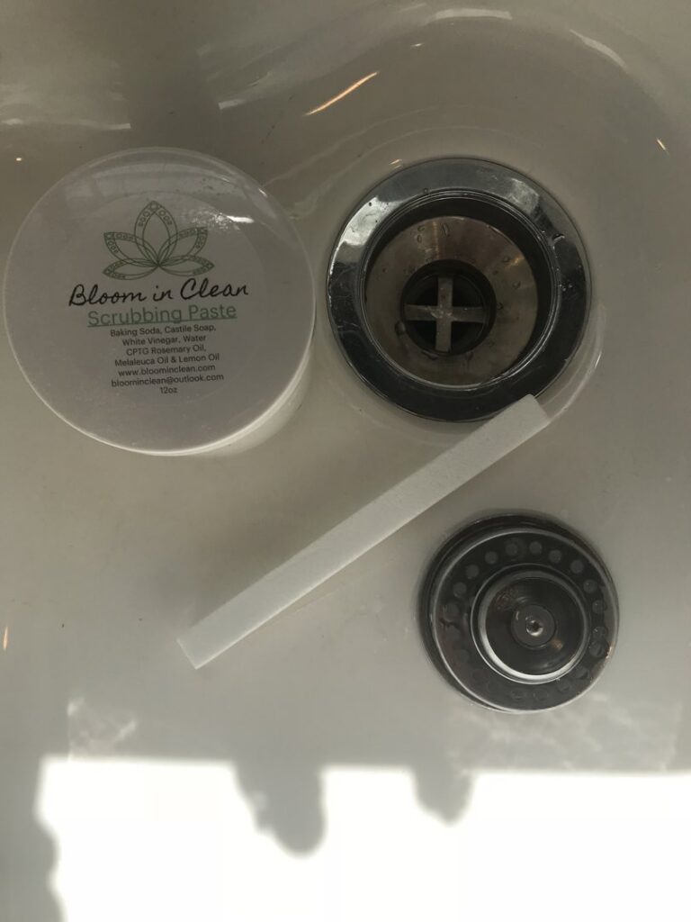 Bloom in Clean scrubbing paste positioned next to a sink drain, ready for effective house cleaning in Bangor, ME.