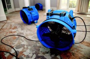 Blue air movers actively drying a room with a concrete floor, demonstrating water damage restoration by Central Oregon Disaster Restoration in Bend, OR.