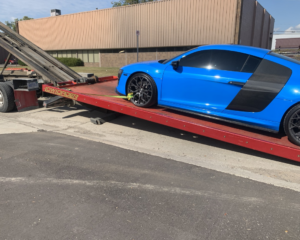 A blue Audi R8 sports car being loaded onto a flatbed tow truck by Triple D's Towing in Sterling Heights, MI.