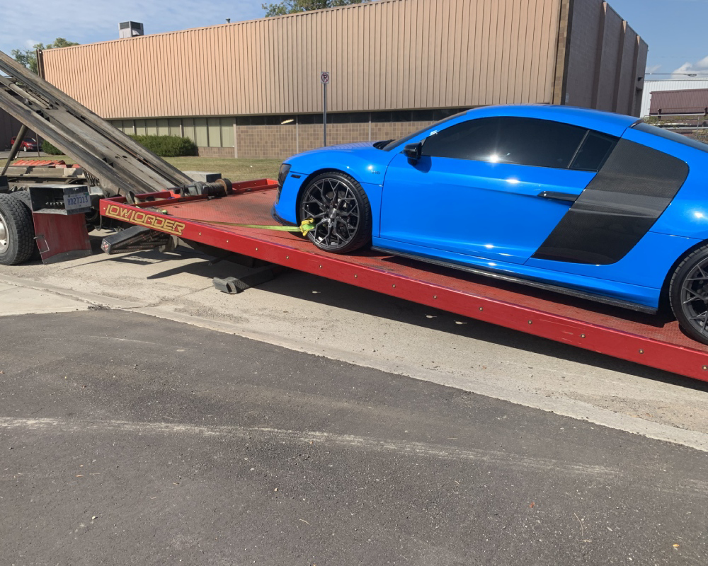 A blue Audi R8 sports car being loaded onto a flatbed tow truck by Triple D's Towing in Sterling Heights, MI.
