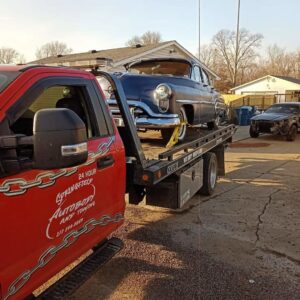 A blue classic car being transported on a flatbed tow truck by Springfield Autobody and Towing in Springfield, IL.