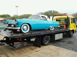 A blue classic Ford Thunderbird being transported on a Tow Jam flatbed tow truck in Dallas, TX.