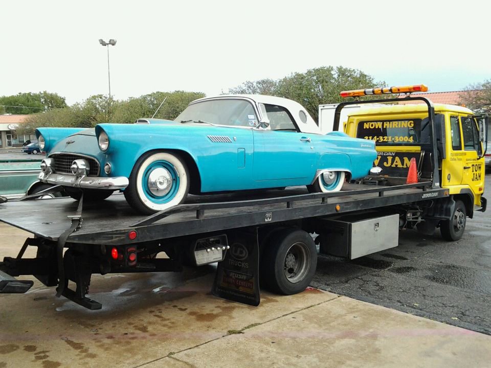 A blue classic Ford Thunderbird being transported on a Tow Jam flatbed tow truck in Dallas, TX.