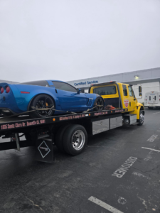 A blue Corvette sports car being transported on a flatbed tow truck by California Auto House in Sacramento, CA.