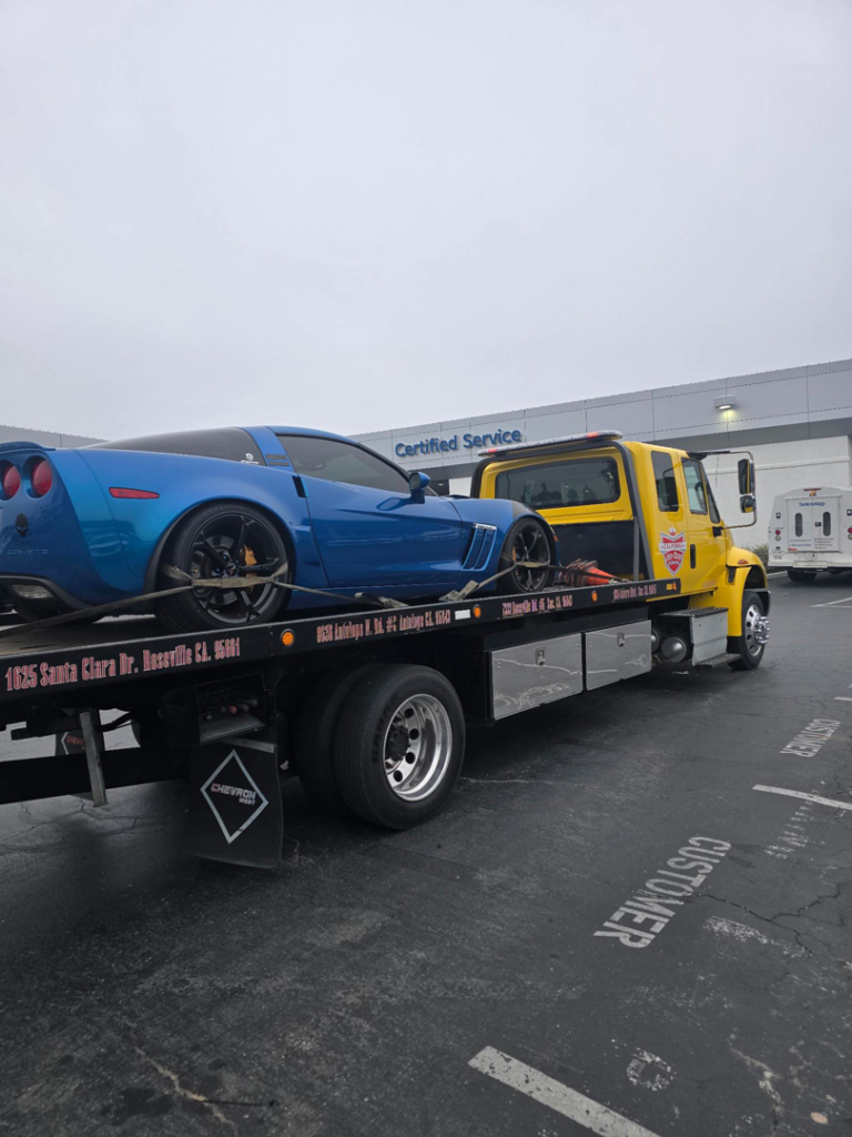 A blue Corvette sports car being transported on a flatbed tow truck by California Auto House in Sacramento, CA.