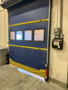 A blue high-speed roll-up door with windows and yellow safety stripes, installed by Canyon Overhead Doors in Salt Lake City, UT.