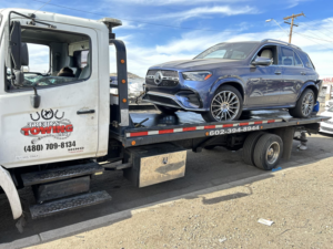 A blue Mercedes SUV being transported on a flatbed tow truck by Trejo's Towing LLC in Phoenix, AZ.
