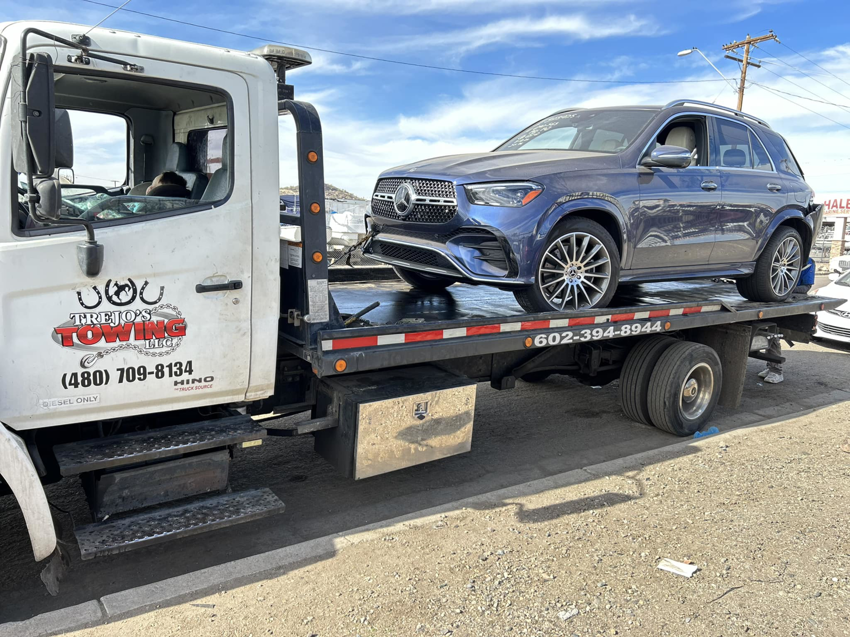 A blue Mercedes SUV being transported on a flatbed tow truck by Trejo's Towing LLC in Phoenix, AZ.