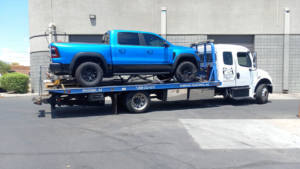 A blue pickup truck being towed on a flatbed tow truck by P&A towing & transport Llc in Phoenix, AZ
