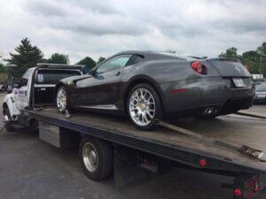 A blue Porsche sports car being transported on a flatbed tow truck by Harpeth Towing & Recovery in Franklin, TN.