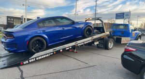 A blue sedan being transported on a flatbed tow truck by Vatos Locos Towing in Cincinnati, OH.