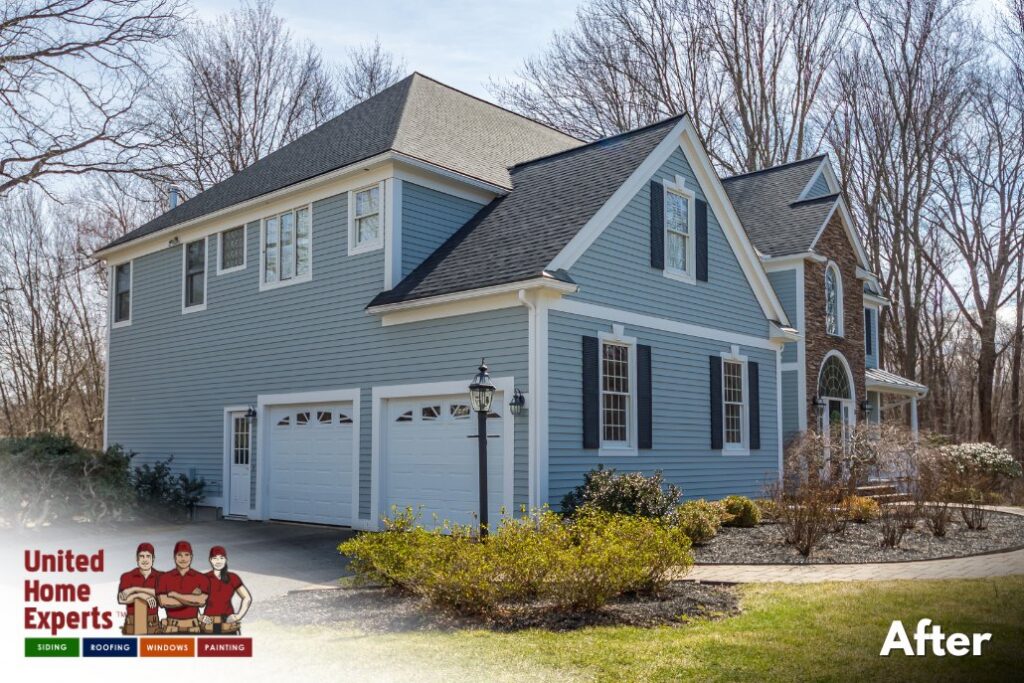 A home with new blue siding and white garage doors, completed by United Home Experts in Ashland, MA.