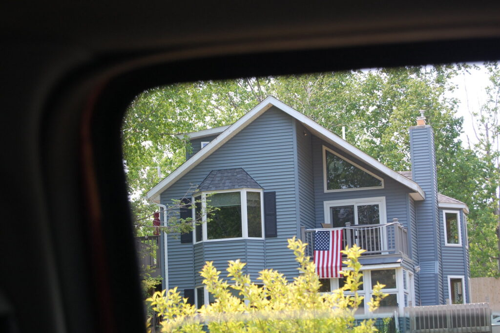 A residential home featuring blue siding and a bay window, completed by Murphy Builders- Genesee County in Ossineke, MI.