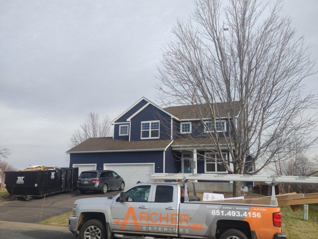 A house with new blue siding and an Archcraft Exteriors contractor truck on site in South Saint Paul, MN.