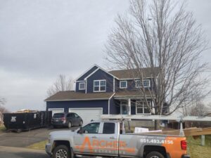 A house with new blue siding and an Archcraft Exteriors contractor truck on site in South Saint Paul, MN.