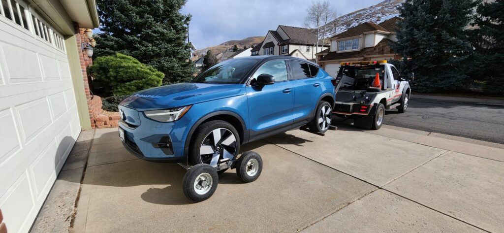 A blue SUV being towed by a wheel-lift tow truck with dollies from A-ROD Towing in Denver, CO.