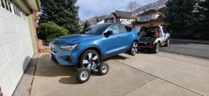 A blue SUV being towed by a wheel-lift tow truck with dollies from A-ROD Towing in Denver, CO.