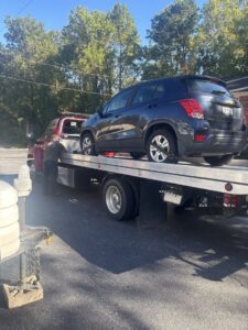 A dark blue SUV being loaded onto a flatbed tow truck by Acme Towing Services in Greenville, SC.