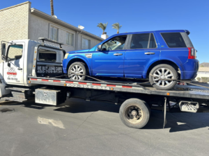 A blue SUV being transported on a flatbed tow truck by Trejo's Towing LLC in Phoenix, AZ.