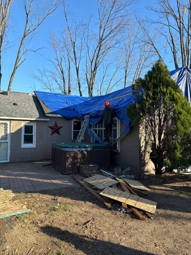 A blue tarp covering a damaged roof, indicating temporary repair by Incore Restoration Group in Wixom, MI, after storm or water damage.