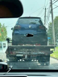 A blue Volkswagen car being transported on a flatbed tow truck by RonniesTowing&Recovery in Bryan, TX